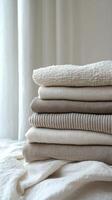 Soft, neatly folded cream colored blankets on a light surface by a neutral backdrop photo