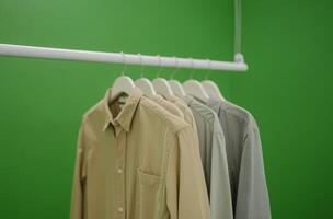 Display of various casual shirts on hangers against a green backdrop in a modern setting photo