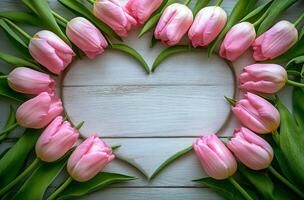 Pink tulips arranged in a heart shape on a light blue wooden surface for a romantic celebration photo