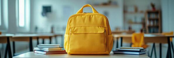 Bright yellow backpack on a table surrounded by books in a modern study area during daytime photo