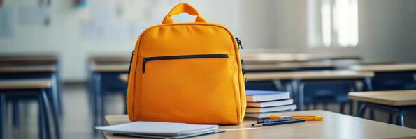 Bright yellow backpack on a table surrounded by books in a modern study area during daytime photo