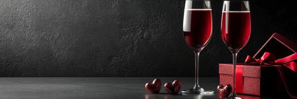 Romantic setting with red wine glasses and gift box for special occasions on dark background photo