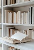 A classic bookshelf filled with vintage books and a large open book on the lower shelf photo