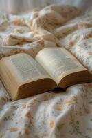 A vintage open book resting on a floral patterned bedspread in soft morning light photo