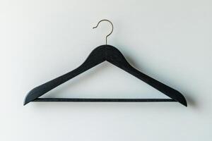 A simple black wooden hanger against a textured gray wall in a minimalist setting photo
