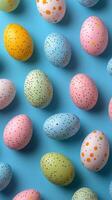 Colorful speckled eggs arranged on a bright blue surface for spring celebration decorations photo