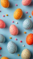 Colorful speckled eggs arranged on a bright blue surface for spring celebration decorations photo