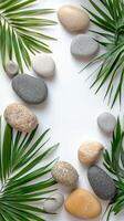 Natural stones and green palm leaves arranged on a light background for a tranquil vibe photo