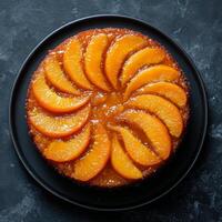 Delicious peach upside down cake served on a black plate in a modern kitchen setting photo