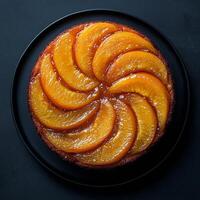 Delicious peach upside down cake served on a black plate in a modern kitchen setting photo