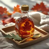 A glass bottle of maple syrup on a wooden board with autumn leaves and a golden spoon photo