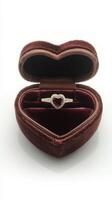Elegant heart shaped ring box with a ruby and diamond engagement ring inside it photo