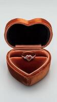 Elegant heart shaped ring box with a ruby and diamond engagement ring inside it photo