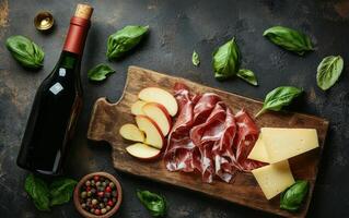 Cured meats, apple slices, basil, and red wine on a wooden board photo