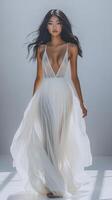 A model walks confidently in a flowing white gown, showcasing elegance and grace in soft lighting photo