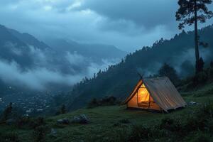 A solitary tent glows warmly in a misty mountain landscape during twilight hours photo