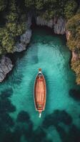 A wooden boat rests gently on clear turquoise waters near a scenic lush hillside during daylight photo