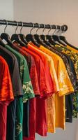 A row of colorful t shirts hanging on a rack in a bright clothing store during the day photo