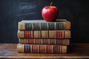 An apple resting on vintage books stacked on a wooden surface against a dark backdrop photo
