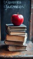 Red apple resting on vintage books stacked on a wooden table in a cozy reading nook photo