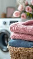 Soft knit sweaters and denim stacked in a wicker basket near a washing machine with flowers photo