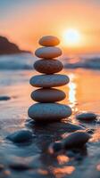 Balanced stones stacked on a beach during sunset with waves gently lapping at the shore photo