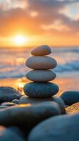 Balanced stones stacked on a beach during sunset with waves gently lapping at the shore photo