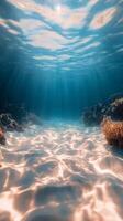 Bright sunlight filters through clear ocean water, illuminating the sandy seafloor and coral reef photo