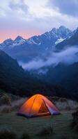 A cozy tent glows warmly in the mountains at dusk surrounded by misty peaks photo