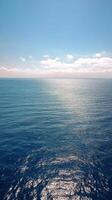 Calm ocean waters reflect the sky on a sunny day with scattered clouds photo