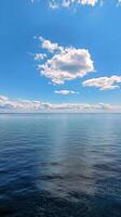 Calm ocean waters reflect the sky on a sunny day with scattered clouds photo