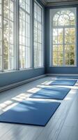 A tranquil yoga studio with blue mats and large windows overlooking autumn trees photo
