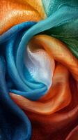 A vibrant close up of silk fabric arranged in a spiral with colors of orange, white, and green photo
