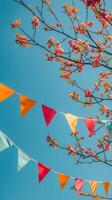 Colorful bunting flags hanging under lush green trees against a vibrant blue sky photo