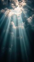Radiant beams of sunlight breaking through dark storm clouds in a dramatic sky during the day photo
