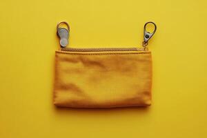 A bright yellow fabric coin purse rests on a vibrant yellow background photo