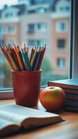 A cozy study corner featuring books, stationery, and a red apple next to the window on a rainy day photo