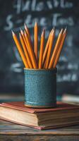 A collection of sharpened yellow pencils arranged in a green can on a wooden desk in a classroom photo