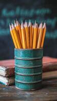 A collection of sharpened yellow pencils arranged in a green can on a wooden desk in a classroom photo