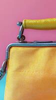 A close up view of a stylish yellow clutch purse with pleats and metallic clasp photo