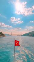 Turkish flag waving on a boat in the Bosphorus with stunning skies and bridge in the background photo