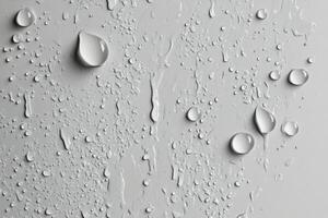 Raindrops on a smooth grey surface creating intriguing patterns and reflections photo