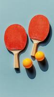 Two red table tennis paddles and a yellow ball on a blue background in a minimalistic arrangement photo