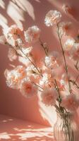 Delicate bouquet of white and pink carnations in glass vase against soft pink background photo