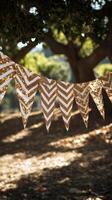 Decorative gold and white bunting strung between trees at a sunny outdoor gathering photo