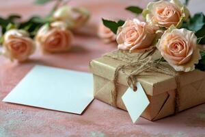 Gift box and pink roses arranged on a pink background with a blank card for writing messages photo