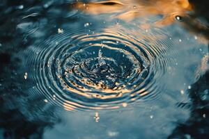 Water droplet creating ripples in a calm, blue surface during a sunny afternoon photo