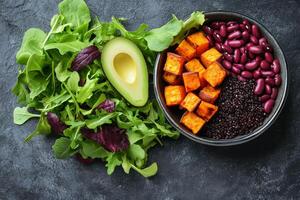Healthy gourmet salad featuring roasted squash, black beans, and avocado with fresh greens photo