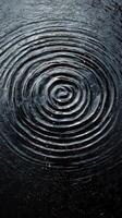 Ripples expanding in dark water under rain creating a calm and tranquil atmosphere photo