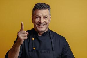 Chef smiling and posing against a bright yellow wall while preparing to share cooking tips photo